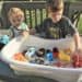 Toddler and Preschooler washing trucks for an outside summer activity