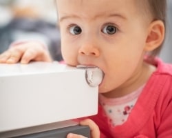 a toddler eating the childproof corner protector