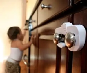 toddler next to a toddler proofed cabinet with cabinet locks