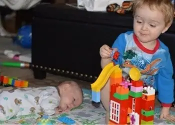 a big brother helping his baby brother do tummy time
