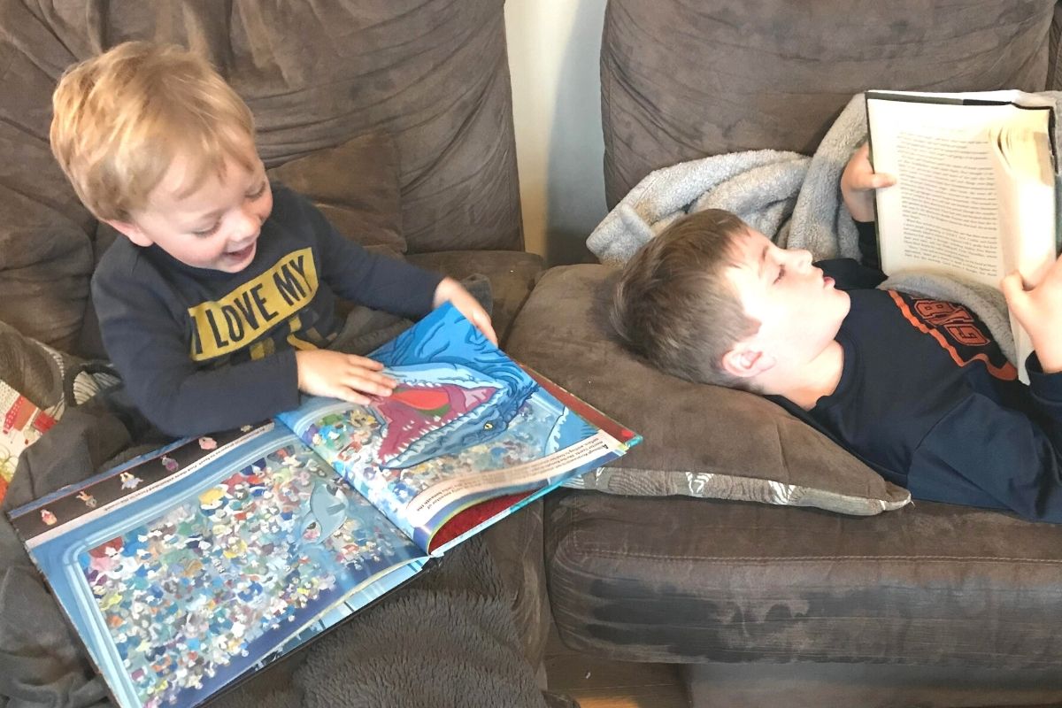 a preschool boy and elementary boy laying down for bedtime reading books